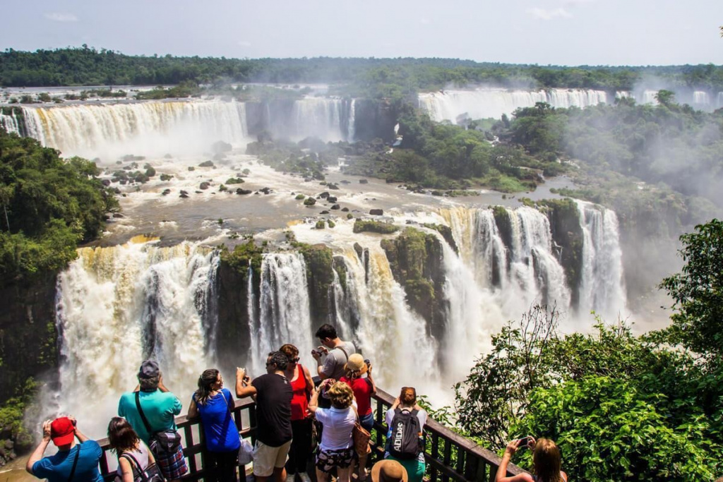 A group of people standing on a railing overlooking a large waterfall AI-generated content may be incorrect.